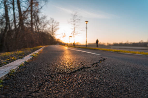 Big crack in asphalt on a bicycle lane during sunset stock photo