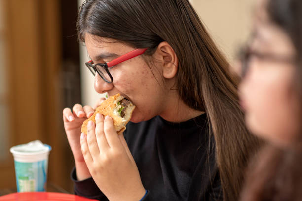 二人の友人がファーストフードを食べている - overweight child eating hamburger ストックフォトと画像
