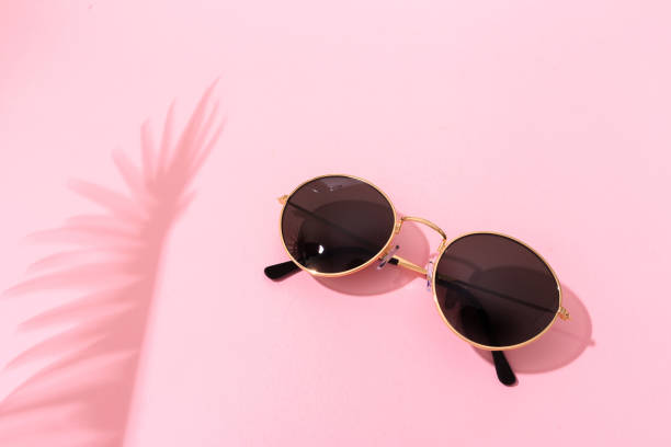 istock round shape black sunglasses on pink background with tropical leaf shadow 1217418789
