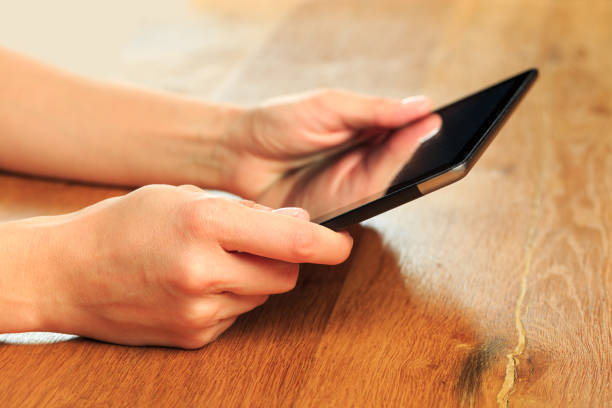 istock female hands holding tablet on wooden background - Image 1217420047