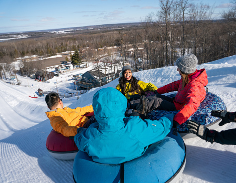 Group of multiracial  millenials snow tubing in the winter in Canada with an active lifestyle