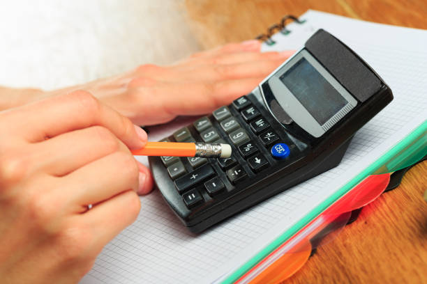 istock female hands working on a calculator on wooden background  - Image 1217420294