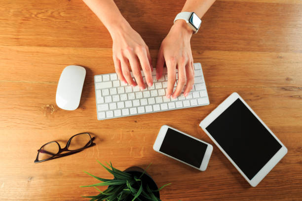 istock Female hands working on wooden work place with modern gadgets  top view - Image 1217422416