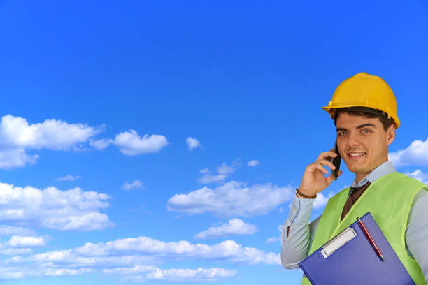 istock Young engineer with helmet  and clipboard, speaking on mobile phone 1217423307