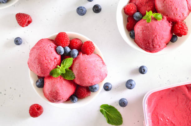 istock Raspberry ice cream scoop with fresh raspberries and blueberries in bowl 1217423607