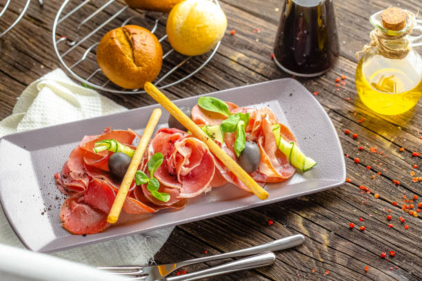 istock rustic wooden background, top and side, cold cuts, bacon and beef appetizer, fresh herbs, bread sticks and olives 1217423768