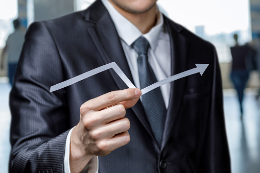 Businessman holds a financial growth arrow on a blurred background.