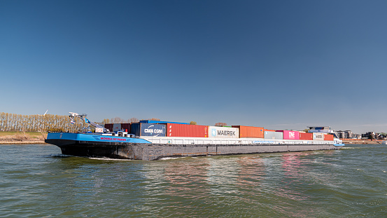 Lobith Netherlands, April 2020, large container vessel on the river rhein near germany with colorful containers on board during a bright day