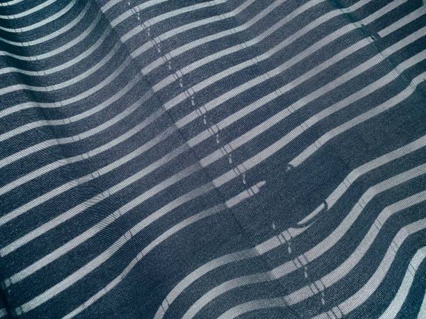 istock Abstract pattern of sunlight and shadow from window blinds on blue-grey curtain 1217424964