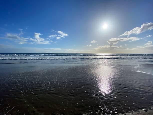 istock Off-center landscape, low sun over the Pacific Ocean, gentle waves roll to shore 1217424981
