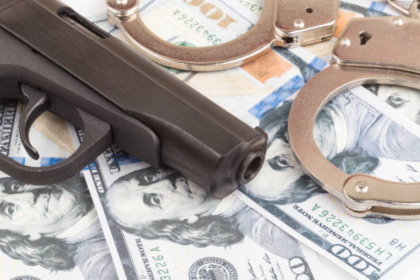 pistolet sur des billets de 100 dollars avec des menottes - currency crime gun conflict photos et images de collection