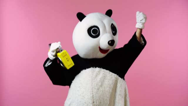 person in panda bear costume dancing with boombox isolated on pink