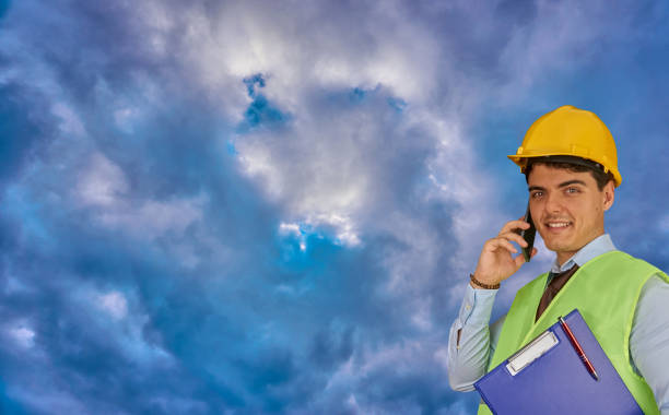 istock Young engineer with helmet  and clipboard, speaking on mobile phone 1217427826