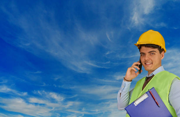istock Young engineer with helmet  and clipboard, speaking on mobile phone 1217427904