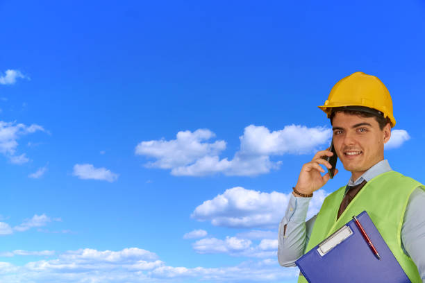 istock Young engineer with helmet  and clipboard, speaking on mobile phone 1217427967
