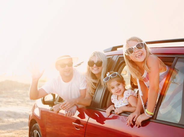 Happy smiling family with daughters in the car with sea background Happy smiling family with daughters in the car with sea background. Portrait of a smiling family with children at beach in the car. Holiday and travel concept family in car stock pictures, royalty-free photos & images