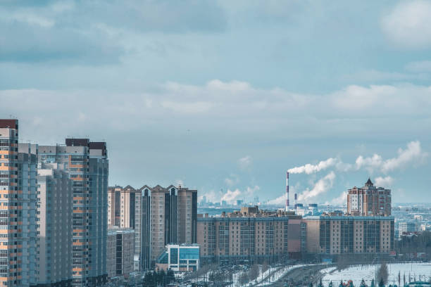 le concept de pollution urbaine par de nombreuses usines en russie fument des tuyaux sur fond de grands bâtiments résidentiels à plusieurs étages - global warming smog city pollution photos et images de collection