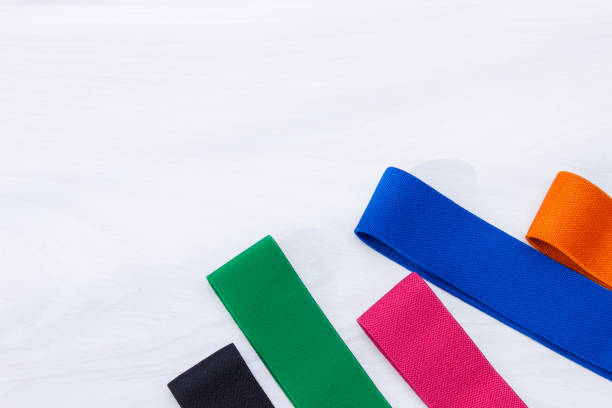 набор разноцветных резинк для фитнеса на белом деревянном фоне. фитнес-тренд, спортивная концепция. - rubber band стоковые фото и изображения