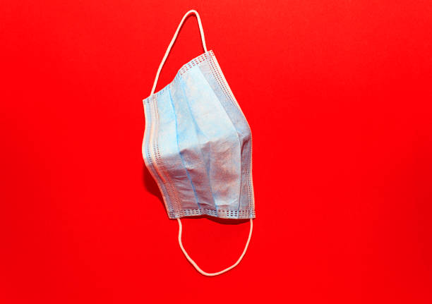 istock White medcine mask lay on a red background 1217429160