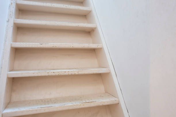 istock Basic white wooden stairs with white wall modern design, needs renovation close-up 1217429418