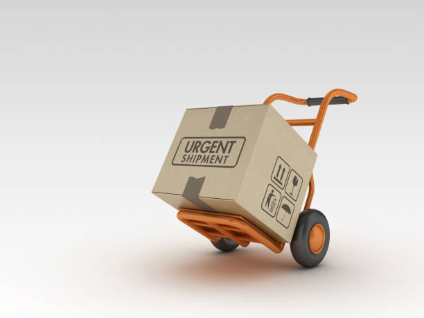 istock Hand Truck and Cardboard Box with URGENT SHIPMENT Label - 3D Rendering 1217430003