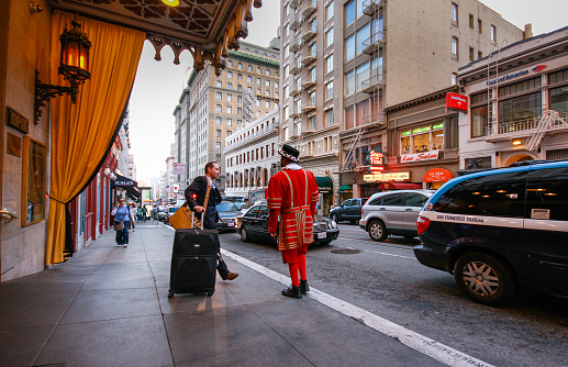 San Francisco, USA - Oct 2, 2012: A departing guest of Kimpton Sir Francis Drake hotel asks a doorman in a beefeater suit to call him a taxi on Oct 2, 2012 in San Francisco, USA.