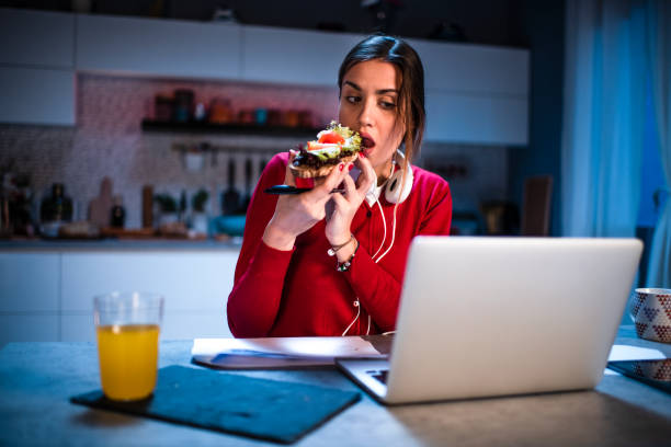istock Young woman having a sandwich while working from home 1217430963