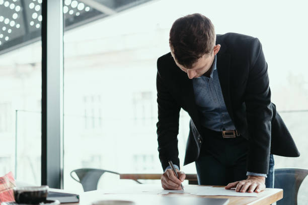 istock Successful business man signing documents in a modern office 1217431338