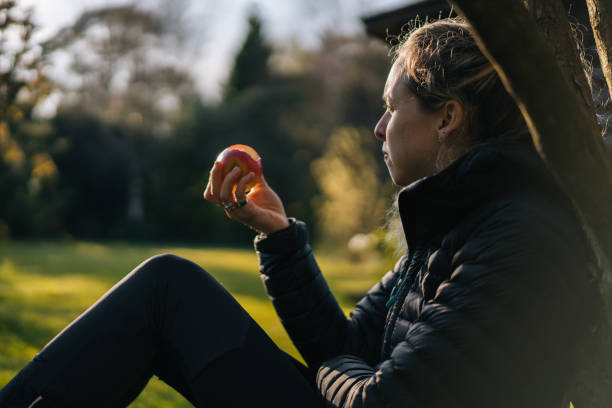 istock Young woman relaxes in garden while eating apple 1217433230