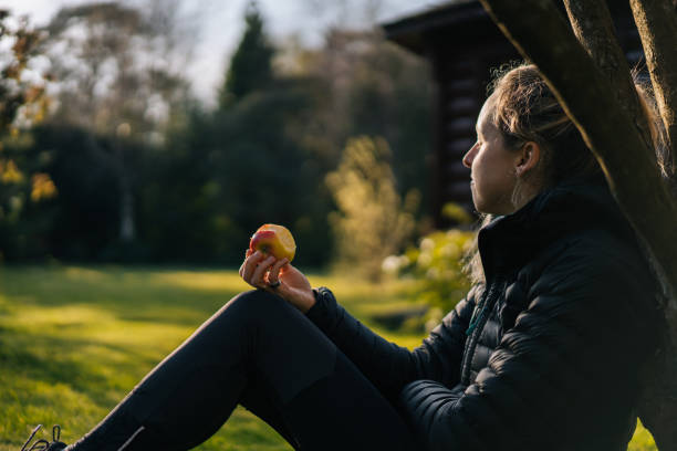 istock Young woman relaxes in garden while eating apple 1217433274