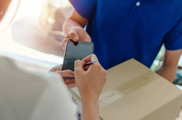 woman customer using pen signature on digital mobile phone with delivery service man in blue uniform for receiving parcel post box from courier at home, express delivery and shopping online concept mujer cliente usando la firma de la pluma en el teléfono móvil digital con el hombre del servicio de entrega en el uniforme azul para recibir la casilla de correos del paquete del mensajero en el hogar, entrega exprés y concepto en línea de compras