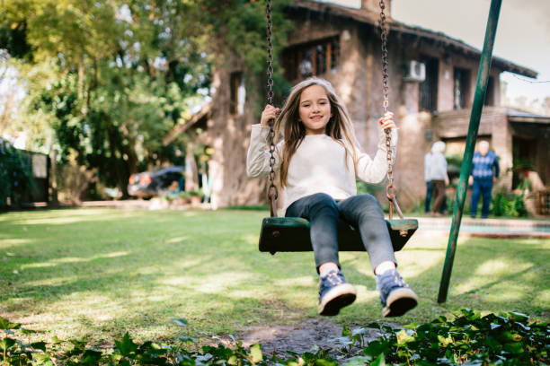 niña jugando en el swing del patio trasero - child swing swinging spring fotografías e imágenes de stock