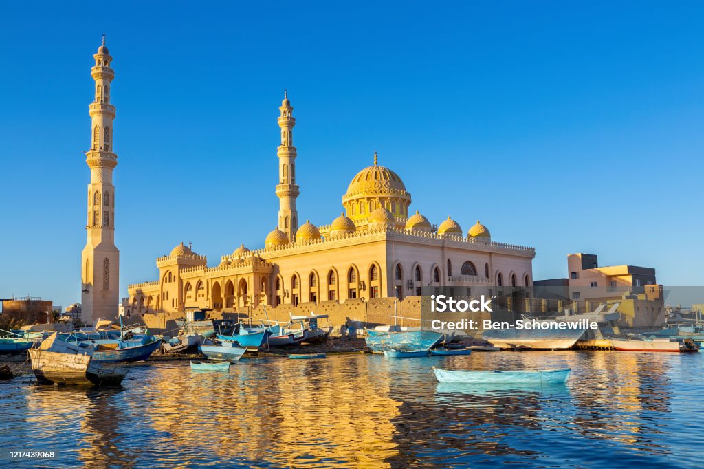 Mosque with fishing boats at sea in egypt Mosque with fishing boats at sea in egyptian landscape. In the city Hurghada in Egypt I took this landscape photo with this new gold colored building. In front of the building there are many little boats floating on the sea water. The view at this coast is very beautiful. Hurghada Stock Photo