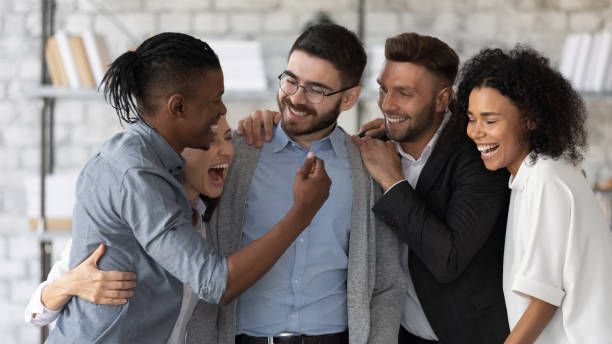 istock Standing and hugging smiling team laughing looking at each other. 1217439294