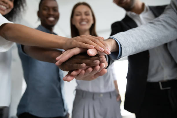 Close up happy diverse business people putting hands together. Close up happy diverse business people putting hands together, showing support and unity. Multiracial colleagues involved in team building activity. Staff training concept, start working together. responsibility stock pictures, royalty-free photos & images