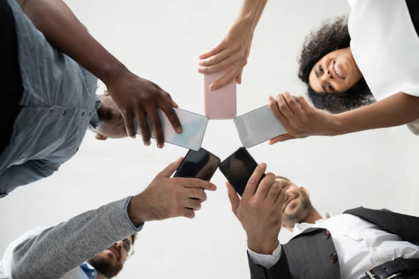 istock Close up diverse team employees using phones together bottom hands. 1217439401