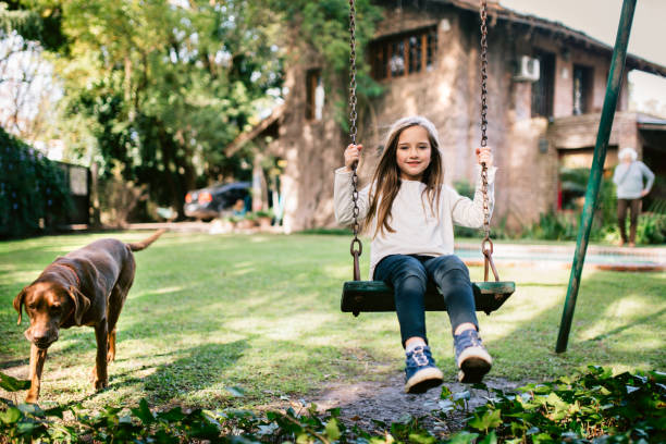 裏庭のスイングで遊んでいる小さな�女の子 - swing child swinging front or back yard ストックフォトと画像