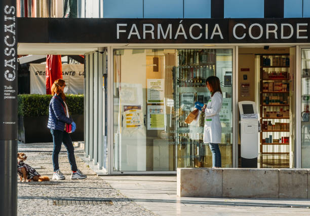 Customer and pharmacist outside a pharmacy in Cascais, Portugal during the Coronavirus Covid-10 epidemic Cascais, Portugal - April 7th, 2020: Customer and pharmacist outside a pharmacy in Cascais, Portugal during the Coronavirus Covid-10 epidemic farmacia stock pictures, royalty-free photos & images