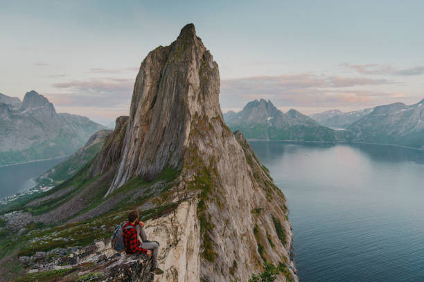 istock Man sitting and looking at Segla   mountain on Senja island 1217444330