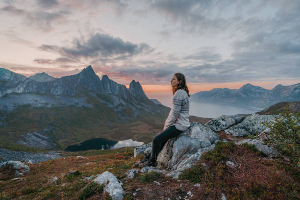 istock Woman sitting and looking at Segla mountain on Senja island 1217444849