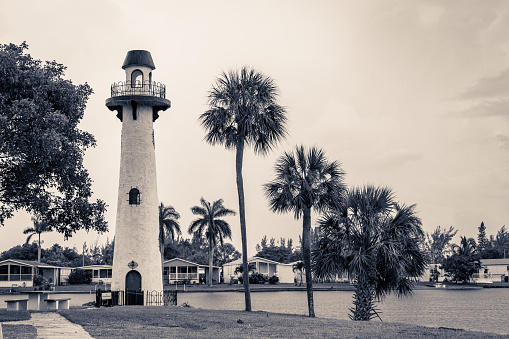 A lighthouse with three palm trees on a lake