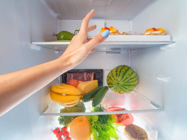 Woman hand picking something from a full open fridge Woman hand picking something from a full open fridge. First person view refrigerated section supermarket photos stock pictures, royalty-free photos & images