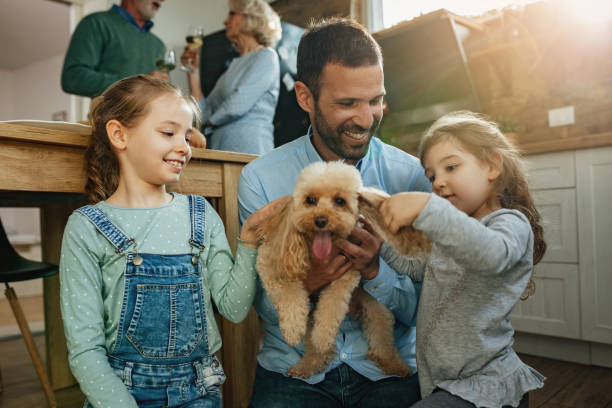 istock Happy father and daughters having fun with a dog at home. 1217450492
