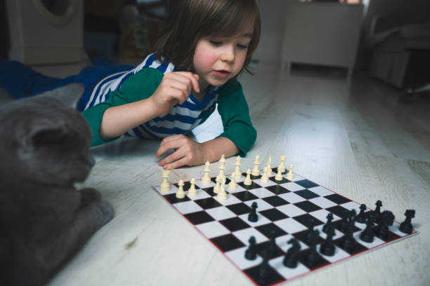 istock Little boy playing chess. Cat next to him. 1217450675