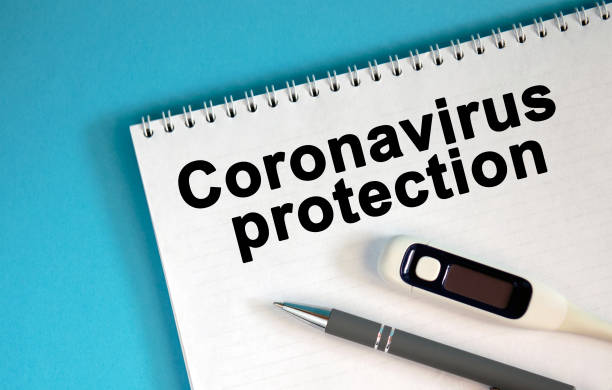 istock CORONAVIRUS PROTECTION - text on a notepad. Lie a pen and a medical thermometer 1217450688