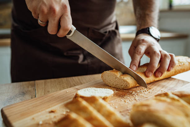 istock Close-up of man cutting bread in the kitchen. 1217450929