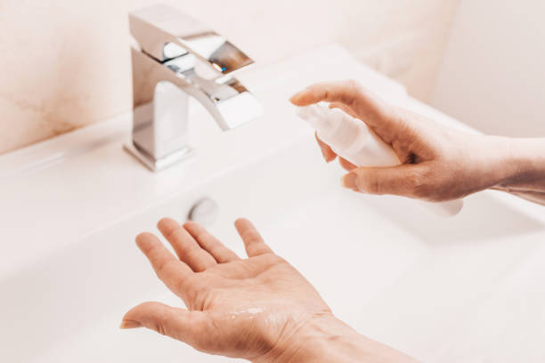 istock Woman sprinkles alcohol antiseptic on her hands 1217452002