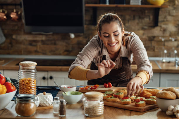 istock Happy woman enjoying while preparing bruschetta in the kitchen. 1217452261