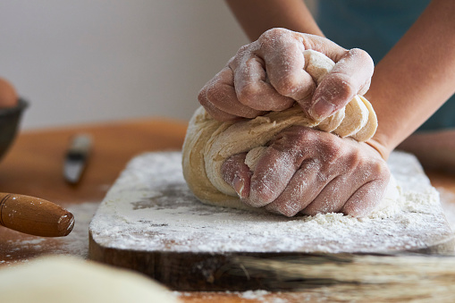 Unrecognizable senior woman preparing dough on counter in kitchen at home