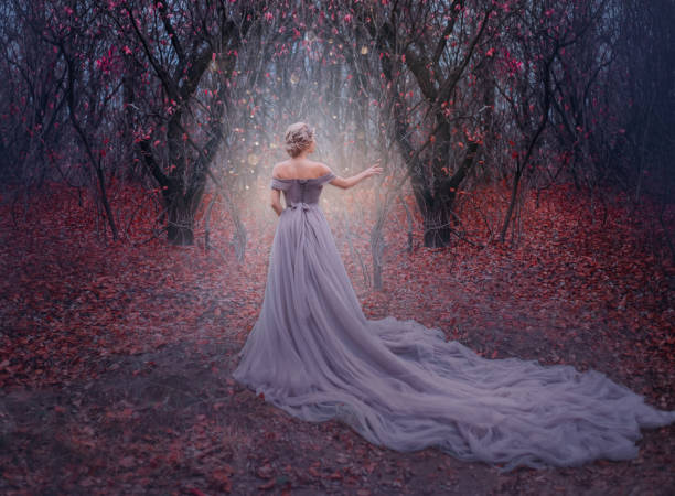 art photo young beauty woman queen. autumn purple mystic tree. fantasy entrance world magic divine glowing in dark deep forest. lady princess in elegant vintage dress, long train back medieval clothes - evening gown imagens e fotografias de stock